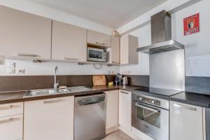 a kitchen with white cabinets and stainless steel appliances at Duplex Tolosa - Pont-Neuf, Dôme de la Grave, 2 BDRs 85m2, AC, Free private car park 200m away - T3 85m2 avec clim, parking couvert gratuit à 200m in Toulouse