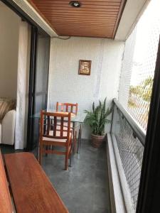 eine Veranda mit einem Tisch und Stühlen auf dem Balkon in der Unterkunft Apartamento no guaruja- praia enseada in Guarujá