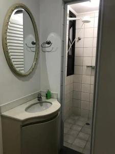 ein Bad mit einem Waschbecken, einem Spiegel und einer Dusche in der Unterkunft Apartamento no guaruja- praia enseada in Guarujá