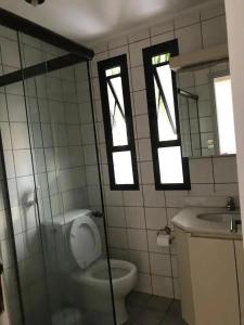 ein Bad mit einem WC, einem Waschbecken und Fenstern in der Unterkunft Apartamento no guaruja- praia enseada in Guarujá