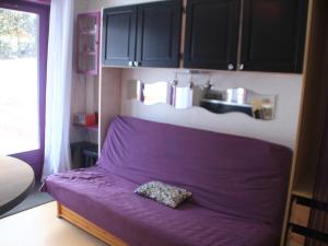 a purple bed in a room with a kitchen at Studio Châtel, 1 pièce, 4 personnes - FR-1-200-362 in Châtel