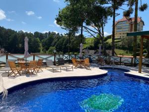 uma piscina com cadeiras e uma mesa e um visor de avisorvisor em Hotel Savoy Excellence em Campos do Jordão