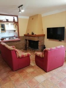 sala de estar con 2 sillas rojas y chimenea en Casa la Nau, en Huesca