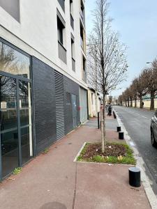 un arbre sur un trottoir à côté d'un bâtiment dans l'établissement Agréable 3 pièces avec Parking à La Courneuve Gare by immo Kit bnb, à La Courneuve