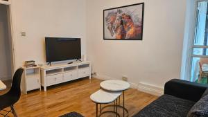 uma sala de estar com uma televisão de ecrã plano num armário branco em Chic Two Bedroom Apartment in the Heart of Battersea Modern and Comfy em Londres