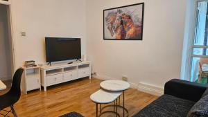 a living room with a flat screen tv on a white cabinet at Chic Two Bedroom Apartment in the Heart of Battersea Modern and Comfy in London