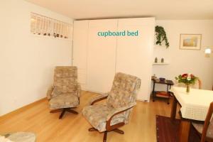 2 Stühle in einem Wohnzimmer mit dem Wordsgrand Bett in der Unterkunft Ferienwohnung in Davos platz WEF 2024 in Bolgen