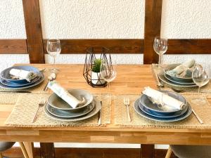 a wooden table with plates and wine glasses on it at Privatunterkunft in Uetersen bei Hamburg in Uetersen