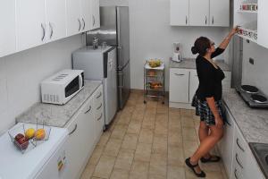a woman standing in a kitchen reaching for a refrigerator at RESIDENCIA WENUIKAN in Santiago