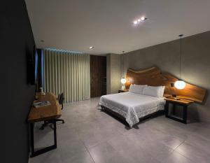 een slaapkamer met een bed, een tafel en een bureau bij Hotel Zelva Negra in Medellín