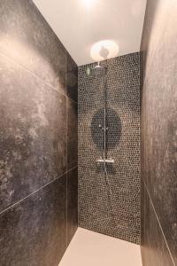 a bathroom with a shower with black tiles at B&B Logie Jolie in Ypres