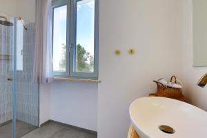 ein weißes Bad mit einem Waschbecken und einem Fenster in der Unterkunft Petra - Sud Est Charme in Andrano