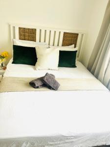 a white bed with green and white pillows at Low budget Cottage- Gqeberha (no loadshedding) in Mount Road