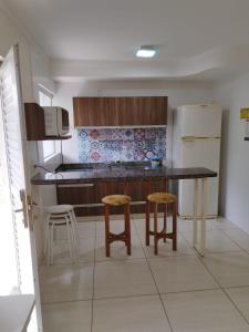 a kitchen with a table and two stools in it at @nobrezafiori Apts particular localizado no LacquaDiroma Sem roupas de cama in Caldas Novas