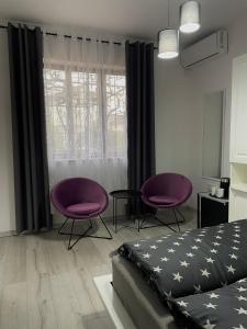 um quarto com duas cadeiras roxas e uma cama em M&M apartments em Tivat