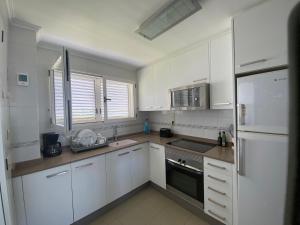 La cuisine est équipée de placards blancs et d'un réfrigérateur blanc. dans l'établissement La casita de la playa, à Oliva