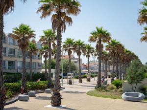 rząd palm w parku z budynkiem w obiekcie Appartement avec piscine et parking, proche des commerces - FR-1-387-189 w mieście Marseillan