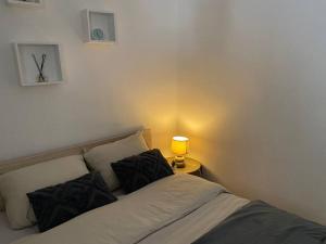ein Bett mit zwei Kissen und einer Lampe auf einem Tisch in der Unterkunft Petit Cosy Aux Portes de Paris, En Face Du M 13 in Asnières-sur-Seine