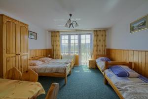 a bedroom with three beds and a window at Dom Wypoczynkowy Pokusa in Tylicz