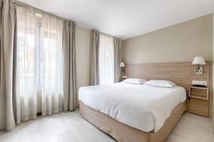 Un dormitorio con una cama grande y una ventana grande. en Marmotel Etoile, en París