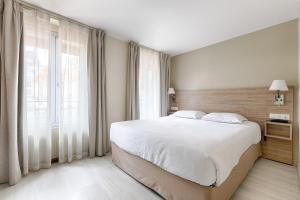 a bedroom with a large bed and a large window at Marmotel Etoile in Paris