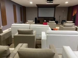リオ・ケンテにあるVeredas do Rio Quente - Flat 726 - Fantástico!!!の白いソファとプロジェクションスクリーンが備わる客室です。