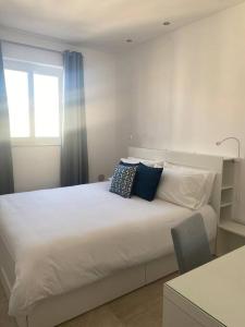 een slaapkamer met een wit bed met kussens en een raam bij Sandstone Apartment 17 in Marsaskala