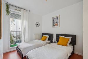 2 camas con almohadas amarillas en una habitación con ventana en Chic and spacious apartment with balcony, en Ivry-sur-Seine
