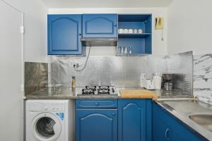 cocina con armarios azules y lavadora en Chic and spacious apartment with balcony, en Ivry-sur-Seine
