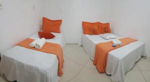 een kamer met 2 bedden met oranje en witte kussens bij HOSTEL SANTOS PRAIA in Santos