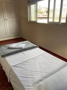 a bedroom with a white bed with a window at Pousada Família Guarapari in Guarapari