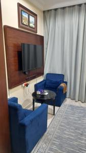 sala de estar con 2 sillas azules y TV en شقق مساكن السمو المخدومة, en Ad Dawādimī