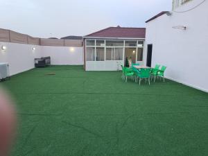 a patio with green grass and a table and chairs at Ayser 1 in Al Madinah