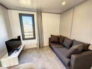 sala de estar con sofá y TV de pantalla plana en Chalet Jullouville, 4 pièces, 6 personnes - FR-1-361-484, en Jullouville-les-Pins