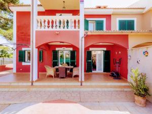 uma casa vermelha com uma mesa de jantar em frente em Belvilla by OYO Villa Malen s Mallorca em Llucmajor