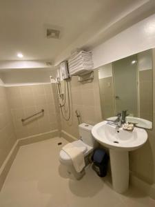 a bathroom with a toilet and a sink and a shower at El Puerto Boracay Shore in Boracay
