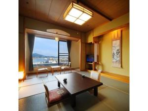 Sun Marine Kesennuma Hotel Kanyo - Vacation STAY 21044v في Kesennuma: غرفة معيشة مع طاولة ونافذة كبيرة