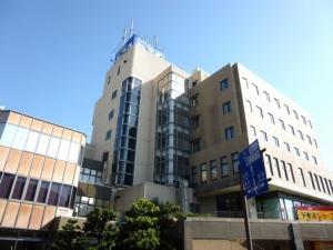 Um edifício alto com um sinal azul à frente. em Hotel Wakow - Vacation STAY 22131v em Yonago