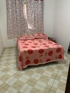 a bedroom with a bed with a pink bedspread at Casa em Unamar Cabo Frio in Cabo Frio
