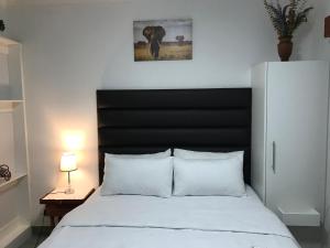 a bedroom with a white bed with a black headboard at The Affectionate One in Louis Trichardt