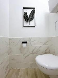 een badkamer met een wit toilet en een foto van een plant bij Colors of life in Torcy