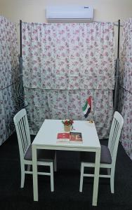 a white table with two chairs and a book on it at Sphinx Hostel in Dubai