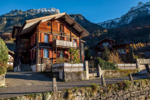 a large wooden house in the mountains with a fence at Chalet Seehus Iseltwald in Iseltwald