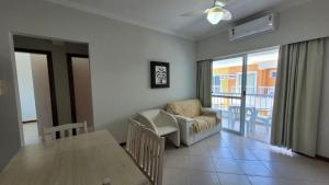 a living room with a table and a chair and a couch at B720 - Apartamento 2 quartos em cond. com piscina in Bombas