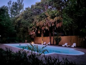 una piscina con sillas, una valla y un árbol en BABAJI Home en Villa Las Rosas
