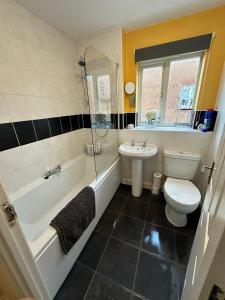 a bathroom with a tub and a toilet and a sink at Entire Modern House in Staffordshire 