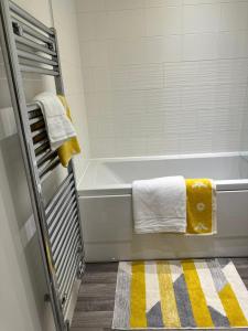 a bathroom with a tub with yellow and white towels at Munalux 2 bed in Birmingham