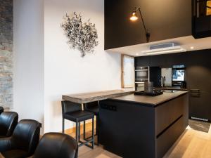 eine Küche mit schwarzen Schränken und eine Bar mit Hockern in der Unterkunft Duplex 4★ 8 pers, 60m des pistes, 4 ch, élégance à La Clusaz - FR-1-304-284 in La Clusaz + 6 Fotos