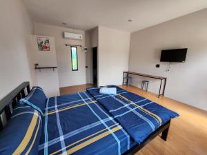 um quarto com uma cama com lençóis azuis e uma televisão de ecrã plano em เช็คอินรีสอร์ท ชัยนาท em Ban Khao Khayai (1)