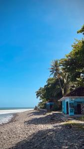 a building on a beach next to the ocean at V & E Home Stay Cimaja Beach in Cimaja